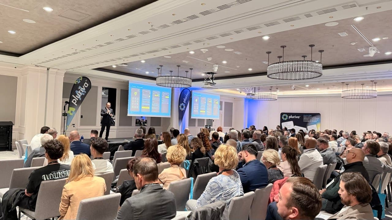 A full room at a Pluriva event, with a speaker on stage presenting Pluriva ERP