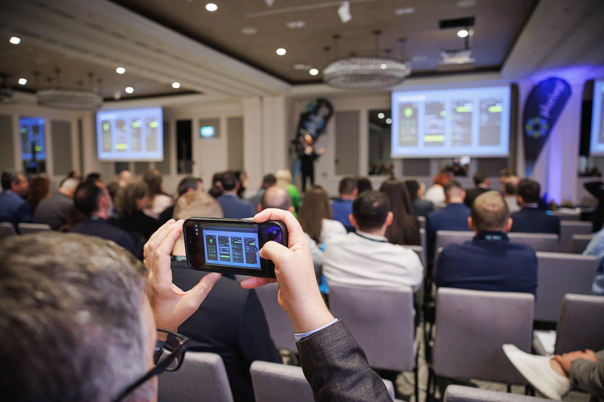 Participant fotografiind cu telefonul slide-ul proiectat în sală
