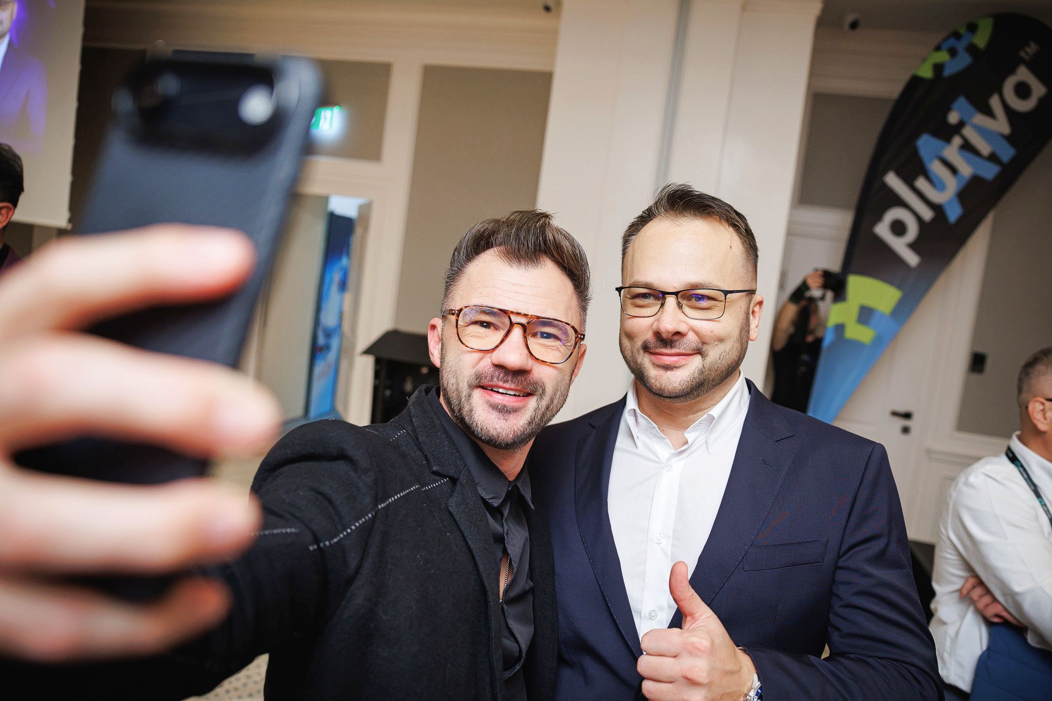 Doi participanți făcând un selfie la conferință